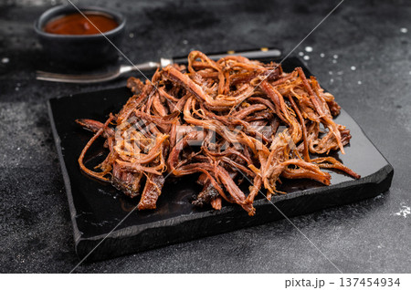 Smoked shredded brisket meat on black stone tray, dried beef strips snack, barbecue style protein food. 137454934