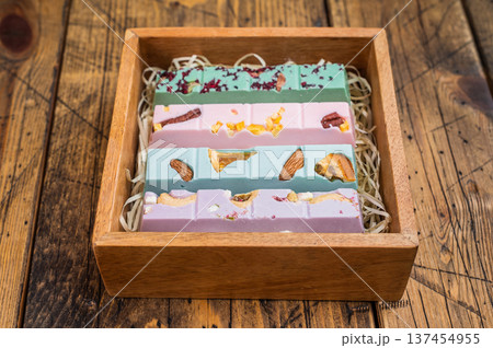 Collection of artisan chocolate bars arranged in wooden box with straw filler on vintage wood background premium sweets Collection of artisan chocolate bars arranged in wooden box with straw filler on vintage wood background premium sweets 137454955