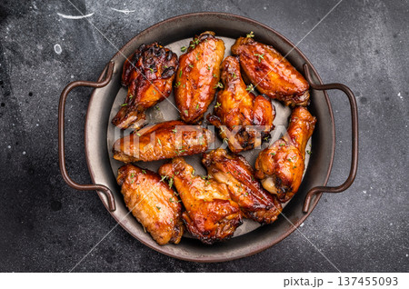 Savory grilled chicken wings smothered in tangy barbecue sauce, the ultimate treat for meat lovers and party enthusiasts. black background. top view Savory grilled chicken wings smothered in tangy barbecue sauce, the ultimate treat for meat lovers and party enthusiasts. black background. top view 137455093