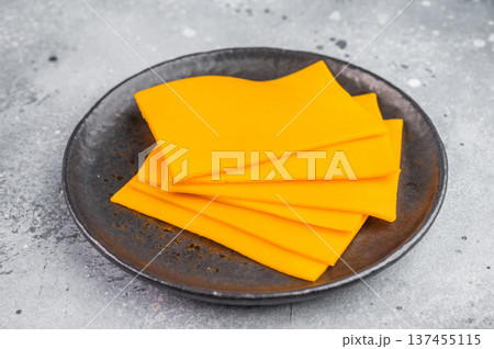 Stack of orange cheese slices on round plate minimal food composition with copy space for menu design or recipes Stack of orange cheese slices on round plate minimal food composition with copy space for menu design or recipes 137455115