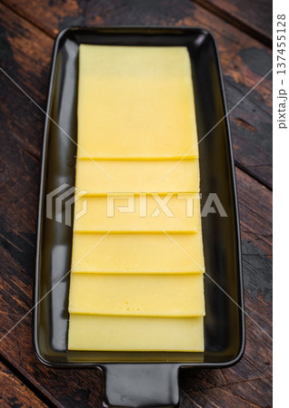Stack of semi hard yellow cheese slices arranged on black tray, dairy ingredient on vintage wooden table background Stack of semi hard yellow cheese slices arranged on black tray, dairy ingredient on vintage wooden table background 137455128