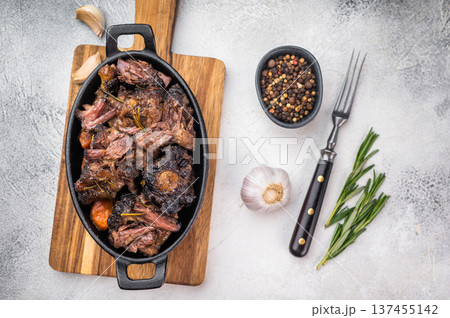 Homemade beef oxtail ragout in cast iron skillet, gelatin rich slow cooked meat with garlic and rosemary Homemade beef oxtail ragout in cast iron skillet, gelatin rich slow cooked meat with garlic and rosemary 137455142