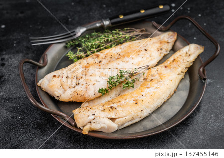 Roasted flaky whitefish fillets with fresh thyme, overhead food photo on moody dark background with copy space. 137455146