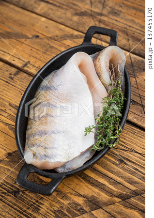 Fresh zander fillet, also known as walleye or pike perch, raw white freshwater fish prepared for cooking in rustic kitchen setting. 137455170