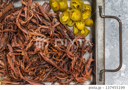 Pulled beef brisket with barbecue sauce, jalapeno and pickles on metal tray, top view with copy space on light background. 137455199