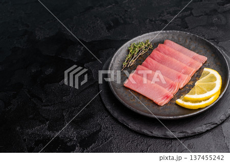 Vibrant tuna sashimi arranged on a plate, showcasing its rich color and delicate texture for an exquisite meal. black background. top view Vibrant tuna sashimi arranged on a plate, showcasing its rich color and delicate texture for an exquisite meal. black background. top view 137455242