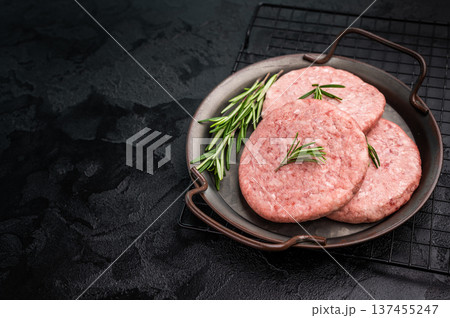 Freshly formed raw meat patty with herbs for burgers, perfect for grilling or frying to satisfy your cravings. black background. top view Freshly formed raw meat patty with herbs for burgers, perfect for grilling or frying to satisfy your cravings. black background. top view 137455247