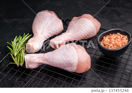 Raw chicken legs drumsticks, perfect for roasting or frying, offering a delicious and juicy flavor in every bite. black background. top view Raw chicken legs drumsticks, perfect for roasting or frying, offering a delicious and juicy flavor in every bite. black background. top view 137455248