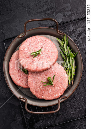 Freshly formed raw meat patty with herbs for burgers, perfect for grilling or frying to satisfy your cravings. black background. top view 137455286
