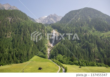 Alpine mountain waterfall flowing through green forest valley in scenic summer landscape Alpine mountain waterfall flowing through green forest valley in scenic summer landscape 137455347