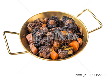 Braised beef oxtail stew with carrots and rosemary in pan on rustic wooden table, rich dark sauce and tender meat 137455398