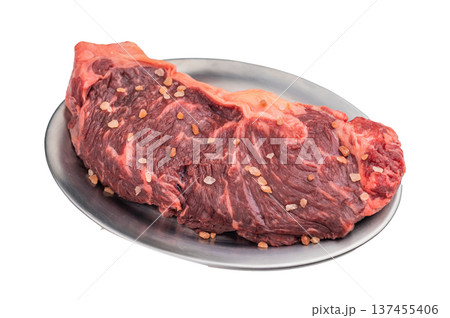 Raw marbled striploin steak with salt crystals on a metal plate over white background, premium beef cut ideal for gourmet cooking. Raw marbled striploin steak with salt crystals on a metal plate over white background, premium beef cut ideal for gourmet cooking. 137455406