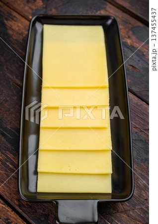 Stack of semi hard yellow cheese slices arranged on black tray, dairy ingredient on vintage wooden table background 137455437