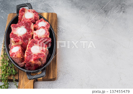 Raw beef oxtail pieces in cast iron skillet with thyme and rock salt, top view butcher style preparation for slow cooking Raw beef oxtail pieces in cast iron skillet with thyme and rock salt, top view butcher style preparation for slow cooking 137455479