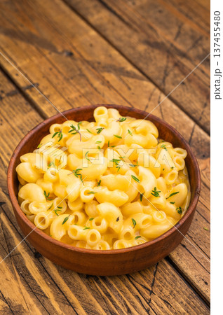 Creamy mac and cheese in a rustic bowl on a wooden table, garnished with fresh thyme, Creamy mac and cheese in a rustic bowl on a wooden table, garnished with fresh thyme, 137455480