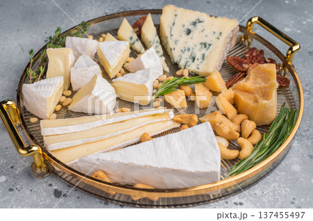Assortment of Brie creamy Camembert and blue Roquefort served with nuts and fresh rosemary on a textured gray surface. Assortment of Brie creamy Camembert and blue Roquefort served with nuts and fresh rosemary on a textured gray surface. 137455497