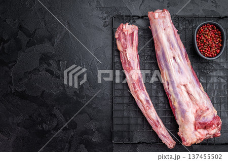 Raw beef oxtail segments on metal rack over dark textured background with copy space, butcher meat for broth and slow cooking Raw beef oxtail segments on metal rack over dark textured background with copy space, butcher meat for broth and slow cooking 137455502