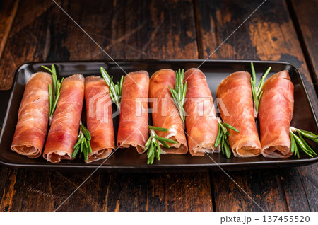 Delicious dry-cured Jamon pork meat served with herbs. Classic overhead view, perfect for a culinary theme. Delicious dry-cured Jamon pork meat served with herbs. Classic overhead view, perfect for a culinary theme. 137455520