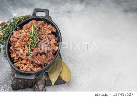 Aromatic wild game meat ragout with thyme and bay leaf in a cast iron pot on a light gray surface perfect for culinary stock images. Aromatic wild game meat ragout with thyme and bay leaf in a cast iron pot on a light gray surface perfect for culinary stock images. 137455527