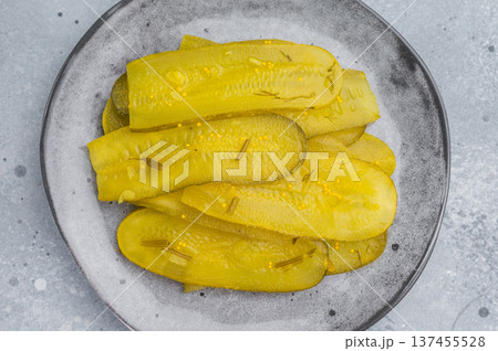 Crisp marinated cucumber slices seasoned with dill and mustard seeds on ceramic plate, top view over stone background. Crisp marinated cucumber slices seasoned with dill and mustard seeds on ceramic plate, top view over stone background. 137455528