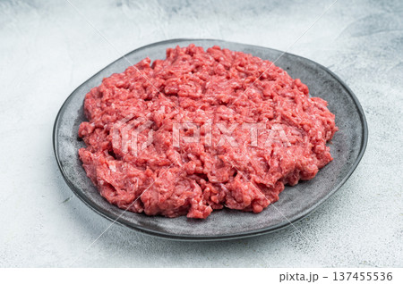 Ground lamb and beef raw meat on gray dish with rosemary against textured concrete backdrop offering detailed texture perfect for grocery and cooking imagery. Ground lamb and beef raw meat on gray dish with rosemary against textured concrete backdrop offering detailed texture perfect for grocery and cooking imagery. 137455536