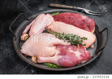 Raw duck parts breast wing thigh and fillet with herbs and garlic in metal pan on dark stone background with fork ideal for poultry stock images. Raw duck parts breast wing thigh and fillet with herbs and garlic in metal pan on dark stone background with fork ideal for poultry stock images. 137455538
