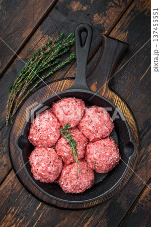 Fresh raw meatballs or Albondiga with thyme in cast iron skillet on rustic wooden background ideal for cooking, protein dishes and food prep themes. Fresh raw meatballs or Albondiga with thyme in cast iron skillet on rustic wooden background ideal for cooking, protein dishes and food prep themes. 137455551