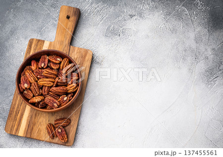 A top view of raw pecan halves in a wooden bowl against a bright white surface offering a minimal crisp composition perfect for recipes and snacking visuals A top view of raw pecan halves in a wooden bowl against a bright white surface offering a minimal crisp composition perfect for recipes and snacking visuals 137455561