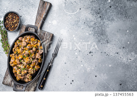 Fried chicken hearts with carrot and herbs in cast iron pan on gray concrete background perfect for food photography. 137455563