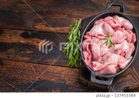 Fresh poultry offal in a cast iron dish, accompanied by aromatic herbs and garlic on a wooden surface Fresh poultry offal in a cast iron dish, accompanied by aromatic herbs and garlic on a wooden surface 137455569