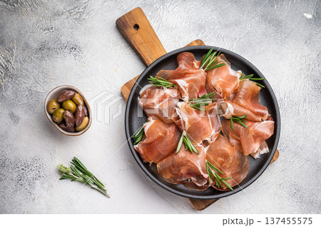 Rustic Charcuterie Board with Jambon Crudo and herbs on a textured stone surface. 137455575