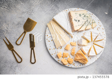 Brie Camembert Parmesan and Roquefort arranged on a terrazzo board against a textured light gray background for a bright gourmet look. 137455578