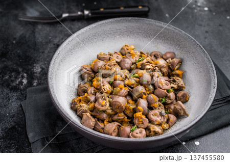 Tasty giblets stew served in gray plate on textured black surface ideal for culinary blogs or traditional meal visuals. Tasty giblets stew served in gray plate on textured black surface ideal for culinary blogs or traditional meal visuals. 137455580