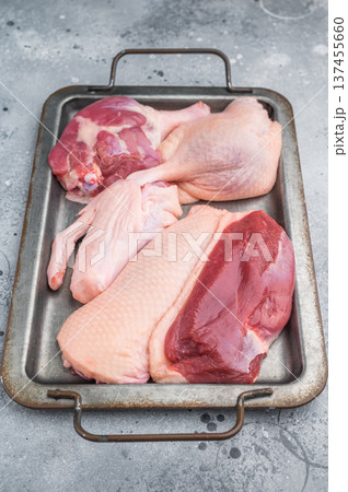 Raw duck parts breast wing and thigh on metal tray over grey stone background ideal for gourmet poultry cooking and stock images. Raw duck parts breast wing and thigh on metal tray over grey stone background ideal for gourmet poultry cooking and stock images. 137455660