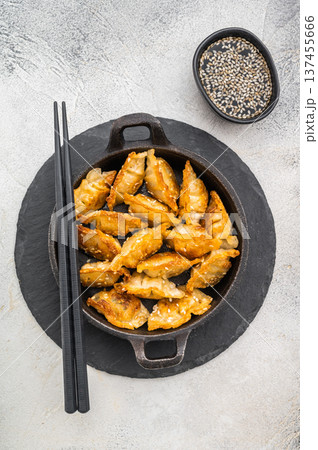 Crispy fried gyoza dumplings with sesame in cast iron skillet on light textured background delicious Asian potstickers top view. Crispy fried gyoza dumplings with sesame in cast iron skillet on light textured background delicious Asian potstickers top view. 137455666