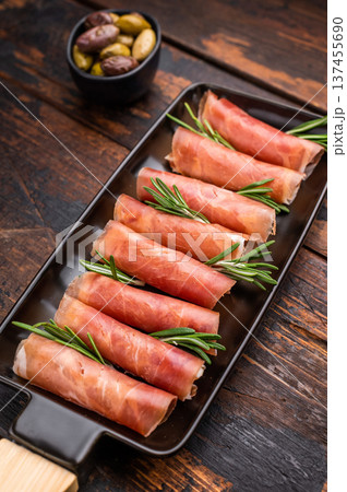 Appetizing plate of thinly sliced cured Italian ham (Prosciutto Crudo) garnished with rosemary sprigs. 137455690