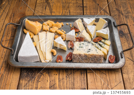Gourmet cheese platter with assorted textures and nuts arranged on vintage metalware over a wooden background. Gourmet cheese platter with assorted textures and nuts arranged on vintage metalware over a wooden background. 137455693