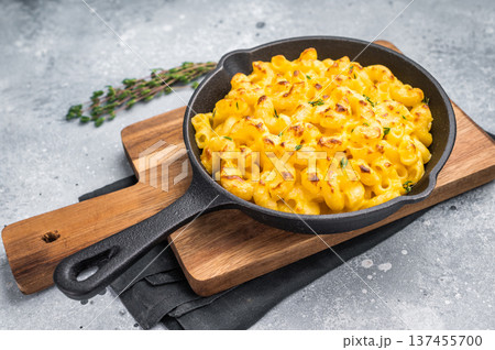Baked mac and cheese in a black skillet on a wooden board. Gray background 137455700