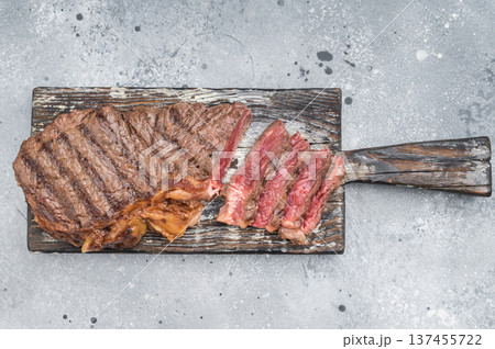 Dry aged New York striploin steak grilled to perfection with herbs and garlic on textured grey surface for culinary concepts. 137455722