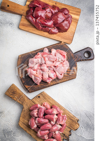 Assorted raw giblets including hearts, liver, and gizzards on vintage wooden boards, organic poultry cooking concept. Assorted raw giblets including hearts, liver, and gizzards on vintage wooden boards, organic poultry cooking concept. 137455752