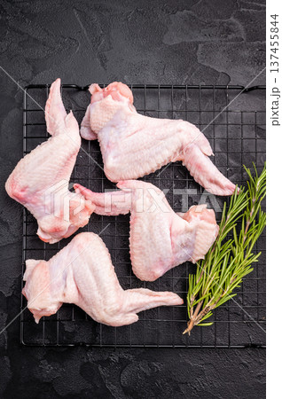 Uncooked chicken wings, showcasing their tender meat, ideal for flavorful recipes and delicious appetizers. black background. top view Uncooked chicken wings, showcasing their tender meat, ideal for flavorful recipes and delicious appetizers. black background. top view 137455844