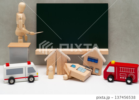 黒板を示すデッサン人形と地震で倒壊した住宅と救急車両 137456538
