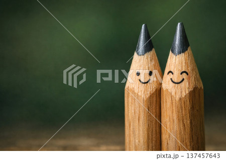 Two smiling wooden pencils on a green background. Space for text. Two smiling wooden pencils on a green background. Space for text. 137457643