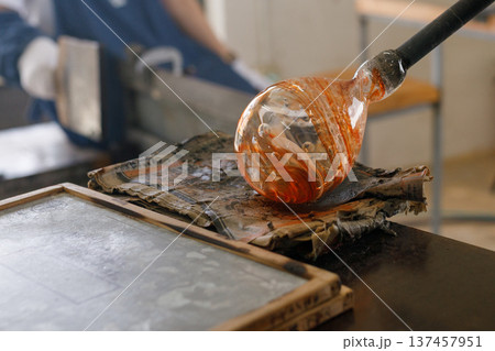 新聞紙を使って形を整える吹きガラス体験の作業風景 137457951
