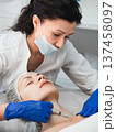 Woman beautician injecting rejuvenating filler into the neck of a female patient in a beauty clinic, close-up 137458097