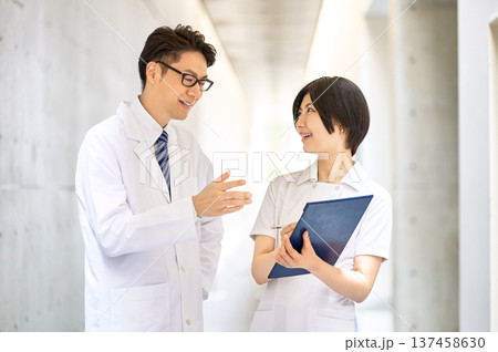 病院の廊下で笑顔で打ち合わせ・相談をする医師と看護師の男女 137458630
