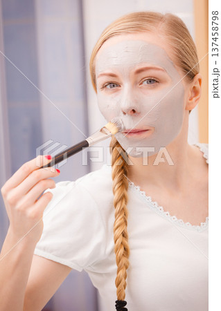 Woman applying with brush clay mud mask to her face 137458798