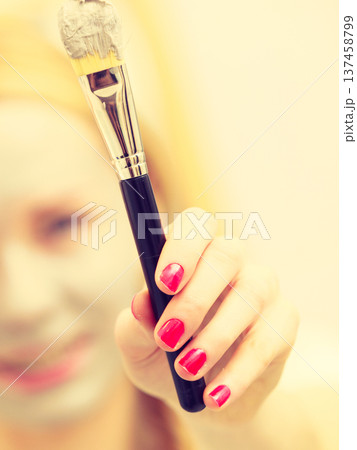 Woman applying with brush clay mud mask to her face 137458799