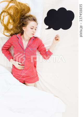 Young woman lying on bed wearing pajamas 137458835