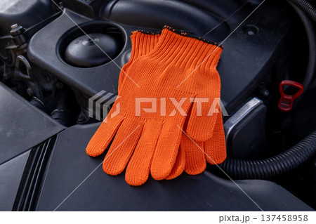 Mechanic gloves are placed on the engine as a worker takes a break from fixing the car on a weekday Mechanic gloves are placed on the engine as a worker takes a break from fixing the car on a weekday 137458958